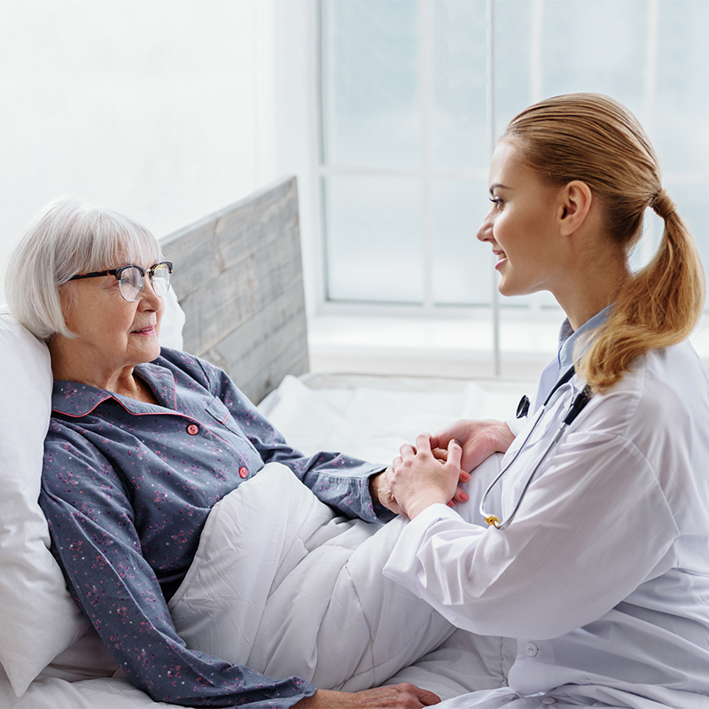 Nurse consulting with a patient and holding her hand.